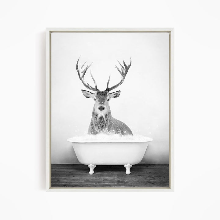 A deer with large antlers is sitting in a white bathtub filled with water, creating a whimsical and unexpected scene.