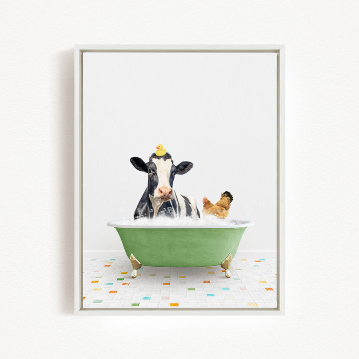 A black and white cow is sitting in a green bathtub filled with bubbles, with a yellow rubber duck perched on its head.
