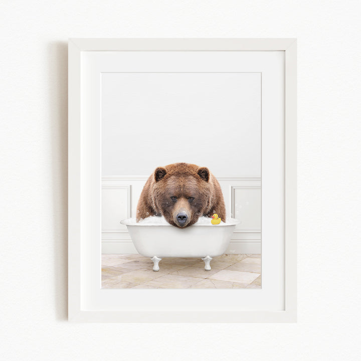 A brown bear is sitting in a white bathtub, surrounded by a yellow rubber duck.