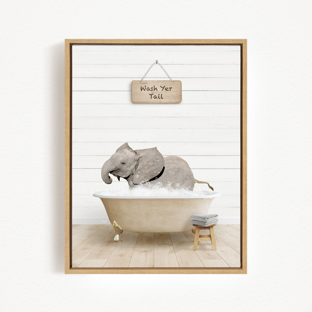 A framed image depicting a gray elephant sitting in a bathtub, with a sign above that reads "Wash Your Tail".