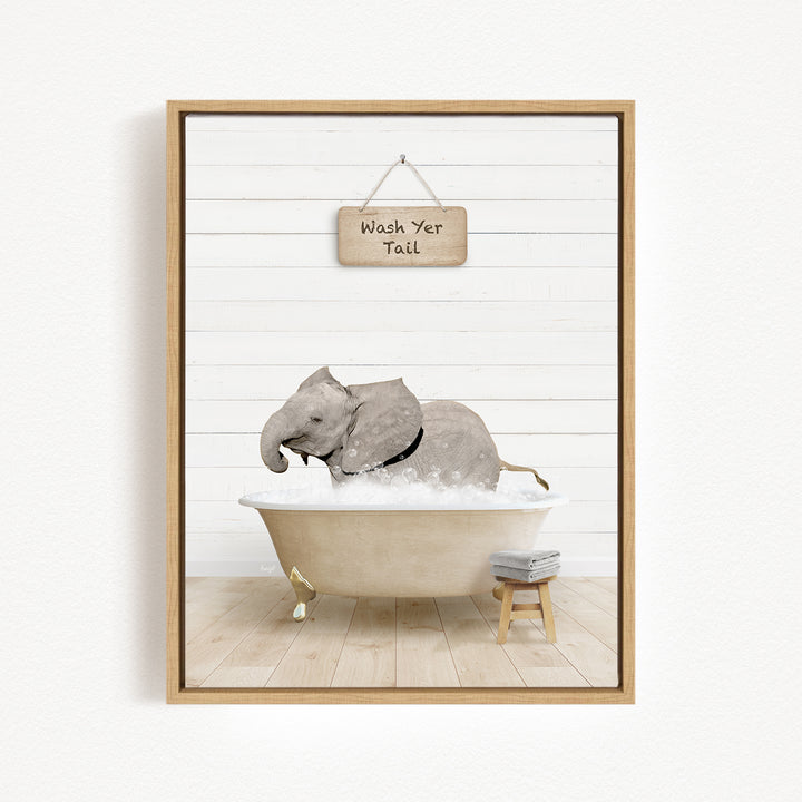 A framed image depicting a gray elephant sitting in a bathtub, with a sign above that reads "Wash Your Tail".