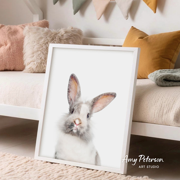 A framed image of a rabbit is displayed in a cozy living room setting with a white couch and colorful pillows.