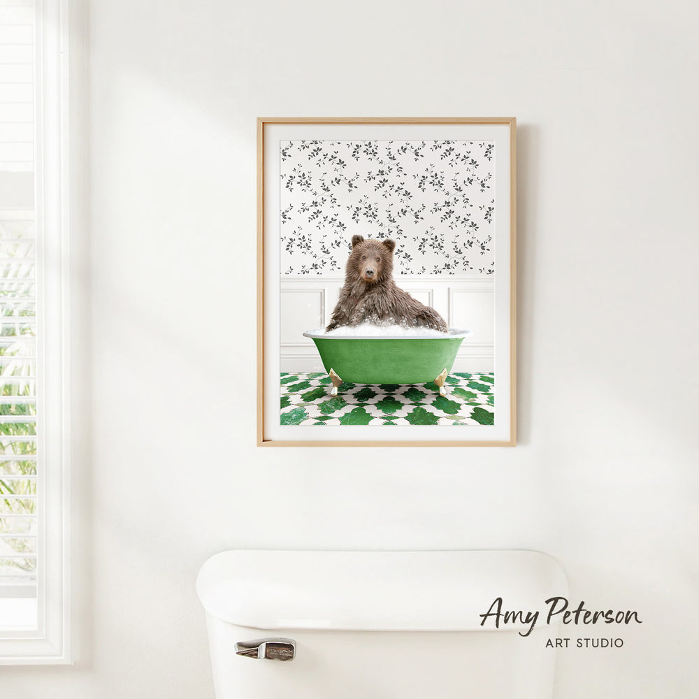 A framed image of a brown bear sitting in a green bathtub, with a patterned wall behind it.