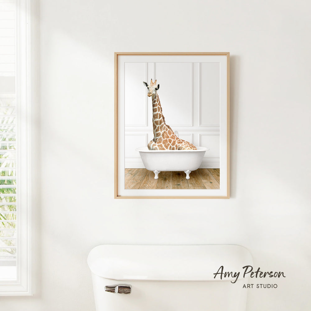 A giraffe sitting in a white bathtub is hanging on a wall, as depicted in the framed artwork.