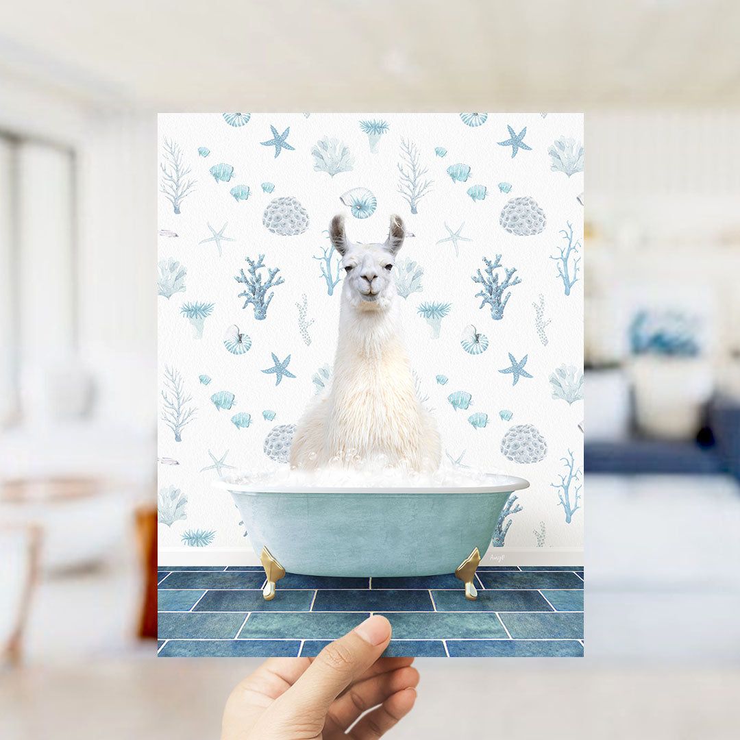 A white llama sitting in a blue bathtub filled with bubbles, surrounded by a pattern of blue and white seashells and starfish.