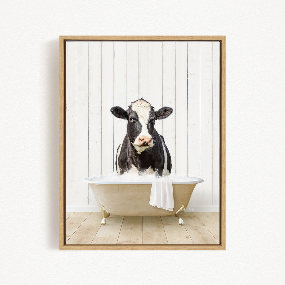 A black and white cow is sitting in a white bathtub filled with water, creating a whimsical and humorous scene.