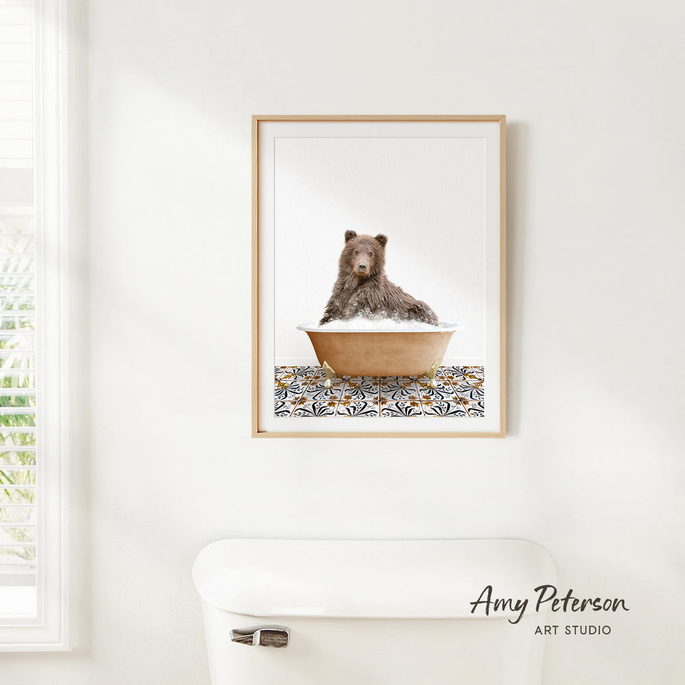 A framed image of a brown bear sitting in a bathtub, with a patterned tile on the floor.