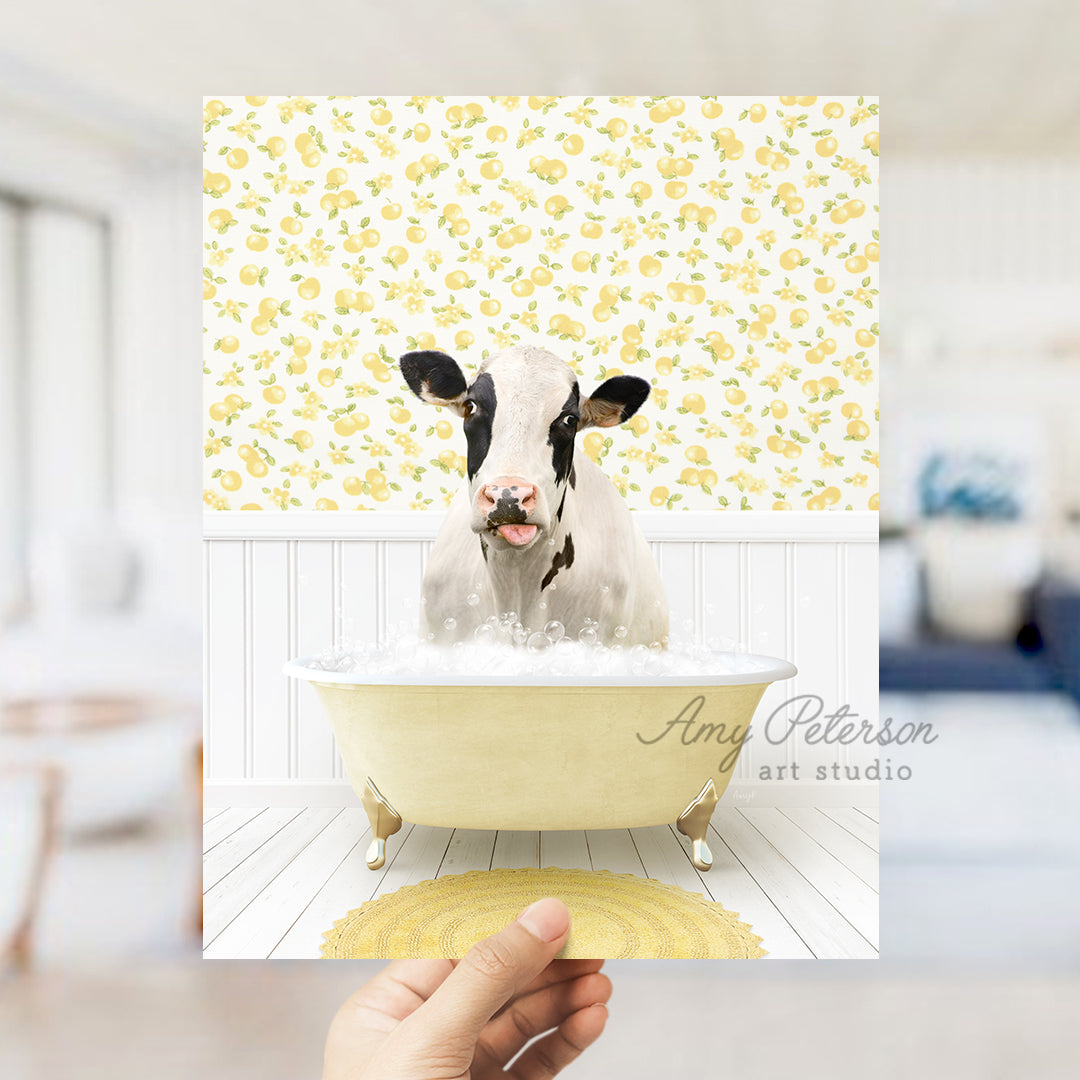 a person holding up a picture of a cow in a bathtub