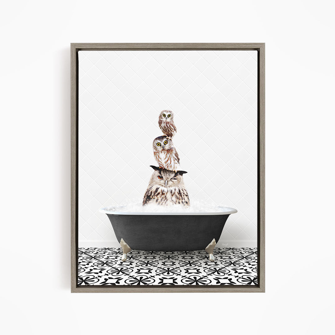 A framed image depicting three owls sitting in a bathtub, with one owl perched on top of the other two.