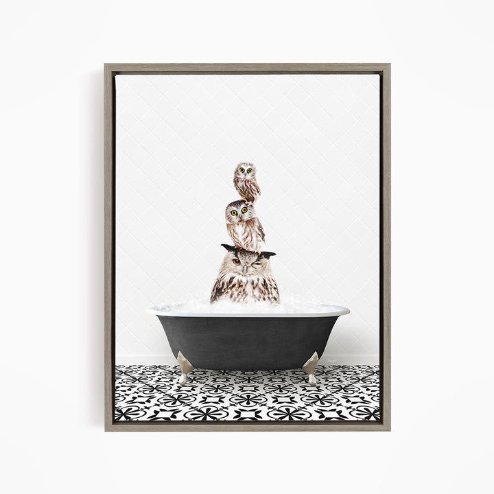 A framed image depicting three owls sitting in a bathtub, with one owl perched on top of the other two.