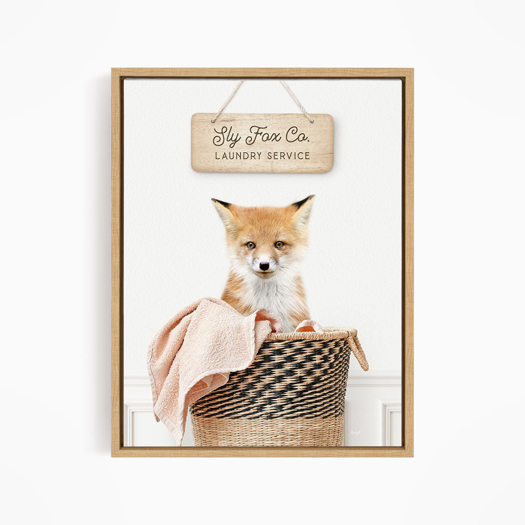 A framed image of a young fox sitting in a woven laundry basket, with a sign above it that reads "Laundry Service".