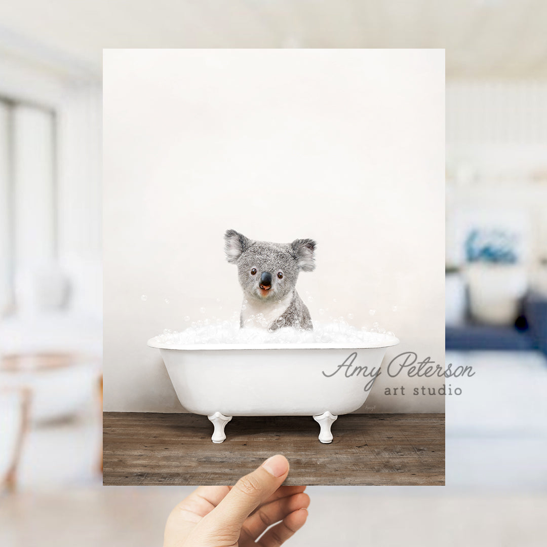 a hand holding a card with a picture of a koala in a bathtub