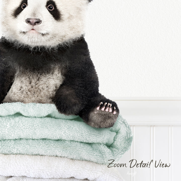 A panda bear sitting on a stack of light blue towels.