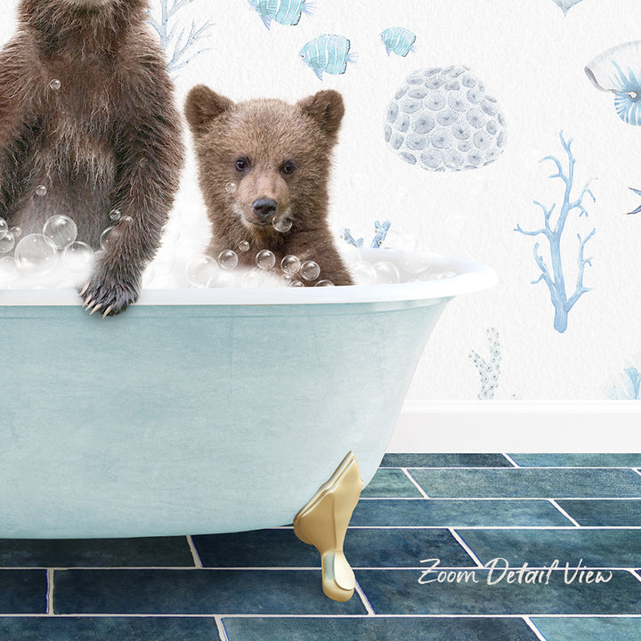A baby bear sitting in a bathtub filled with bubbles, with a wall featuring blue and white marine life designs behind it.
