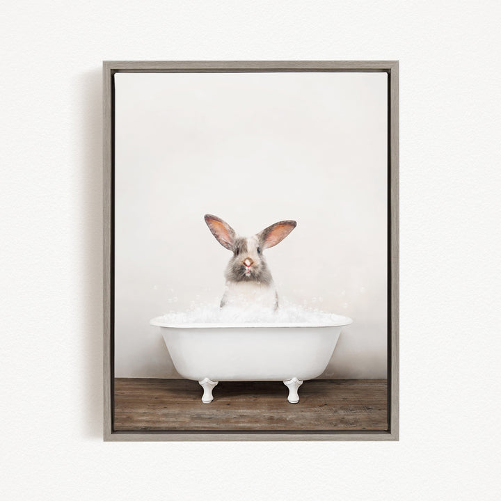 A white rabbit sitting in a white bathtub filled with water, looking directly at the camera.