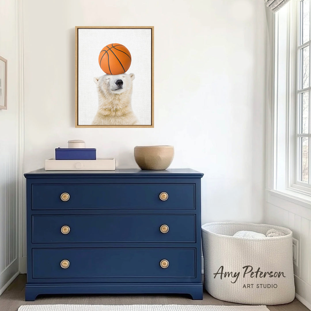 a blue dresser with a framed picture of a polar bear balancing a basketball on its head, and a white basket next to it.