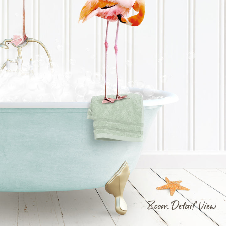 A pink flamingo stands on the edge of a light blue bathtub, with a green towel hanging on the side and a starfish on the floor.