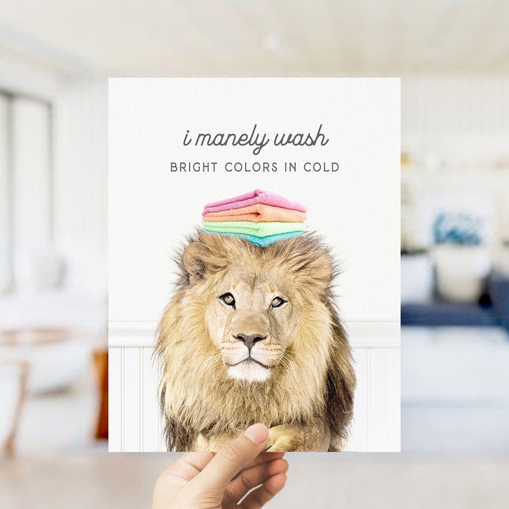 A hand holding a card with a lion's head and a stack of colorful towels on top of it.