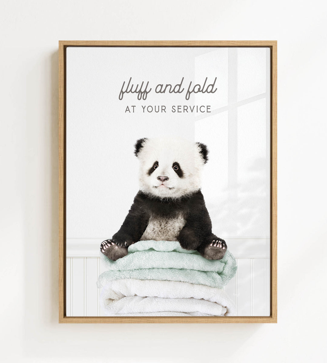 A panda bear sitting on a stack of towels, with the text "fluff and fold at your service" written above the image.
