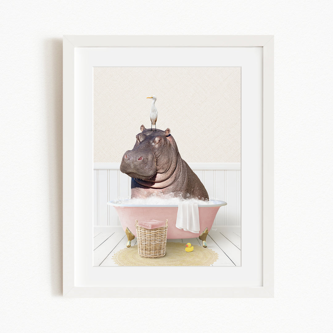 A framed image depicting a hippopotamus sitting in a pink bathtub, with a bird perched on its head.
