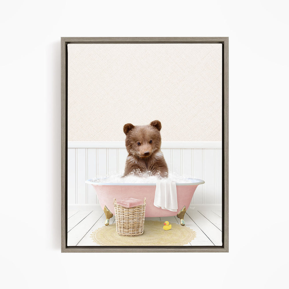 A brown bear sitting in a pink bathtub filled with bubbles, surrounded by a yellow rubber duck and a basket.