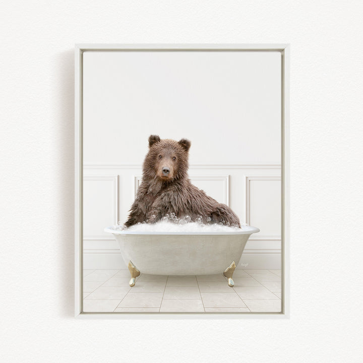 A brown bear sitting in a white bathtub filled with bubbles, looking directly at the camera.