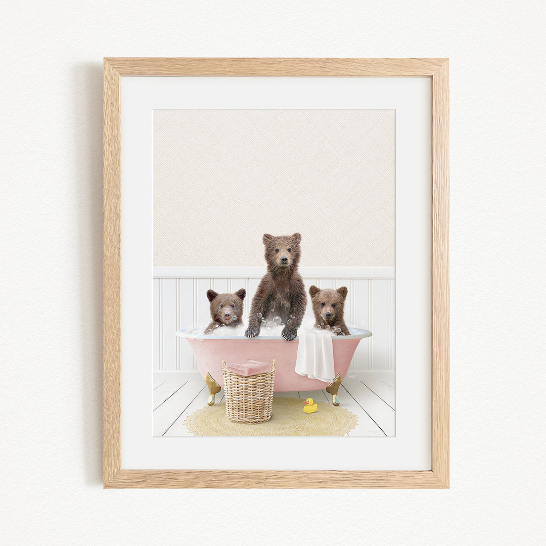 A framed image depicting three bears sitting in a pink bathtub, with a yellow rubber duck floating in the water.