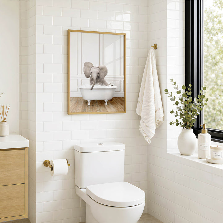 A bathroom with a white toilet, a framed image of an elephant in a bathtub, and a towel rack with a towel.