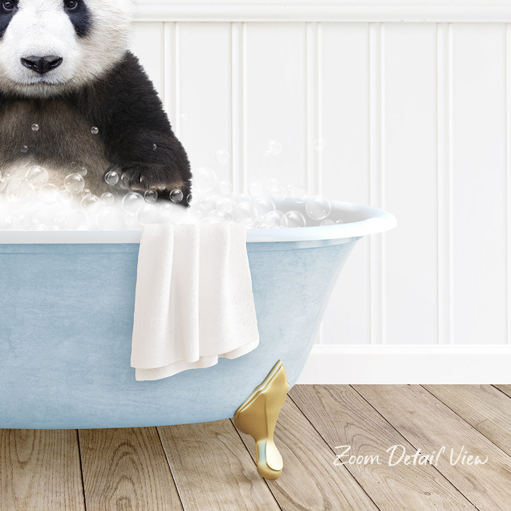 A panda bear sitting in a blue bathtub filled with bubbles, with a towel and gold bathtub leg visible.