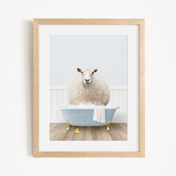 A fluffy white sheep sits in a blue bathtub filled with bubbles, surrounded by yellow rubber duckies.