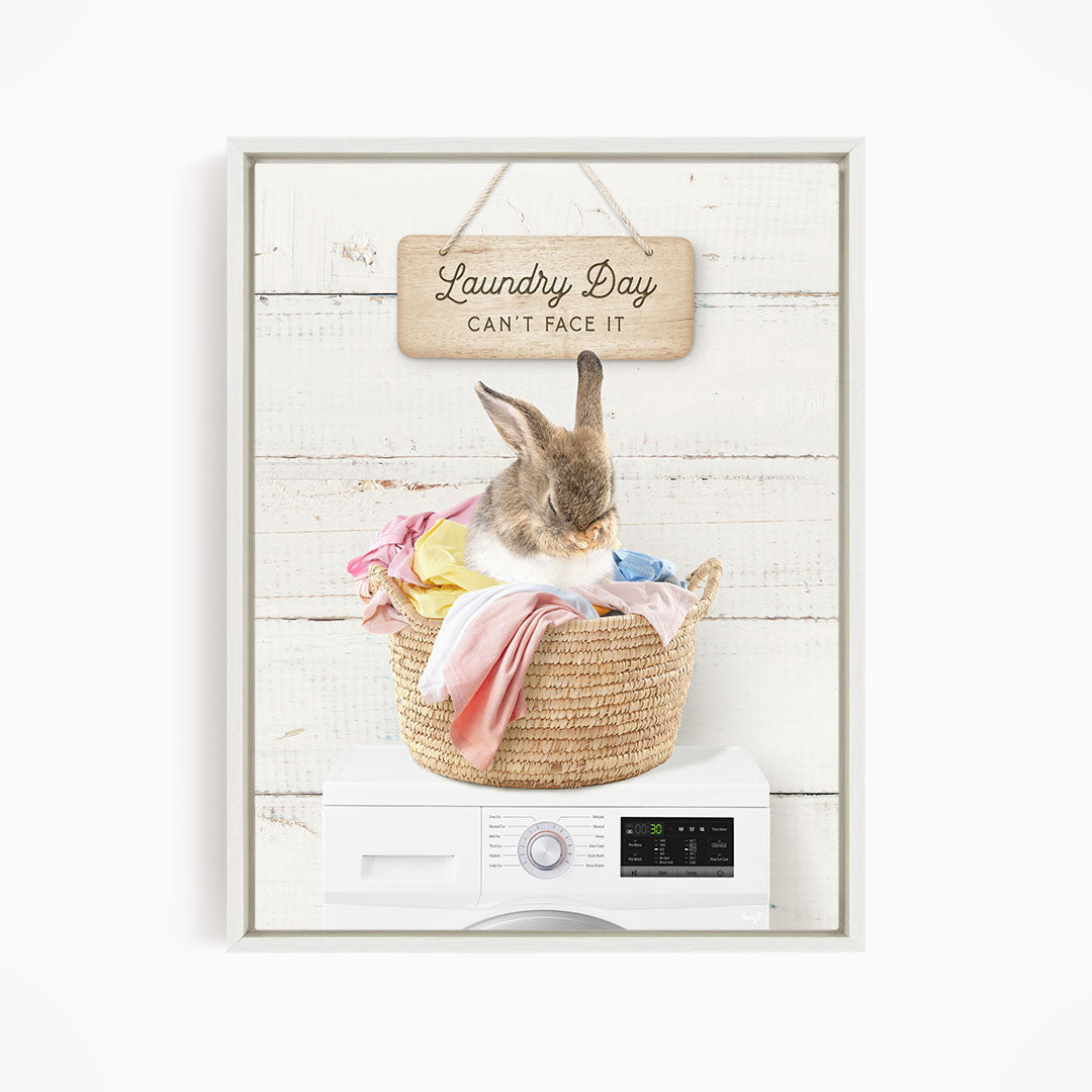 A cute rabbit sitting in a woven laundry basket, with a sign above that says "Laundry Day Can't Face It".