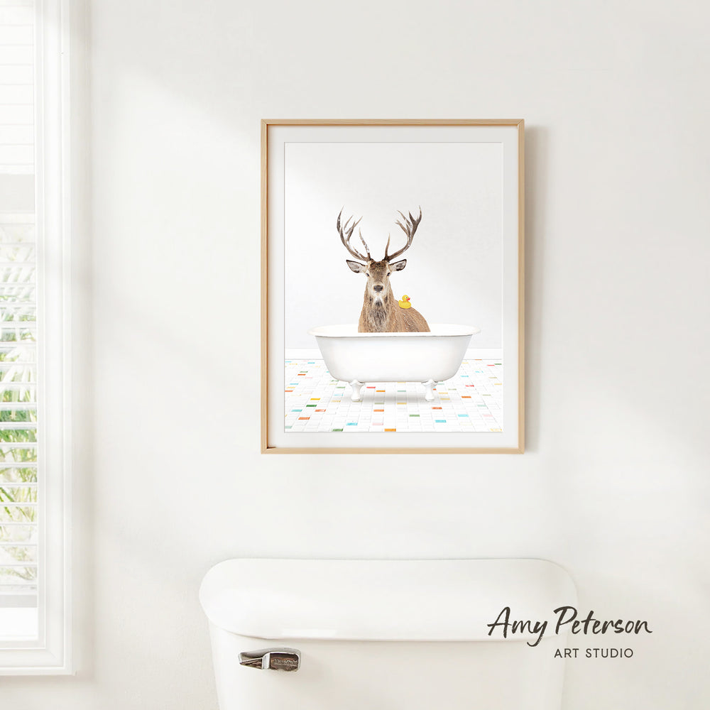 A framed print of a deer sitting in a bathtub, with a yellow rubber duck floating in the water.