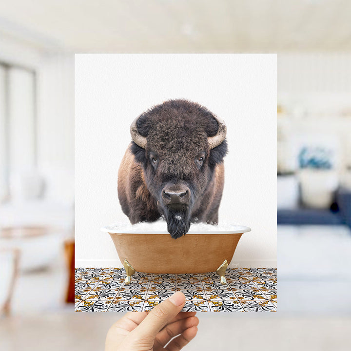 A close-up of a bison's head peeking out of a bathtub filled with water, with a hand holding the image up to the camera.