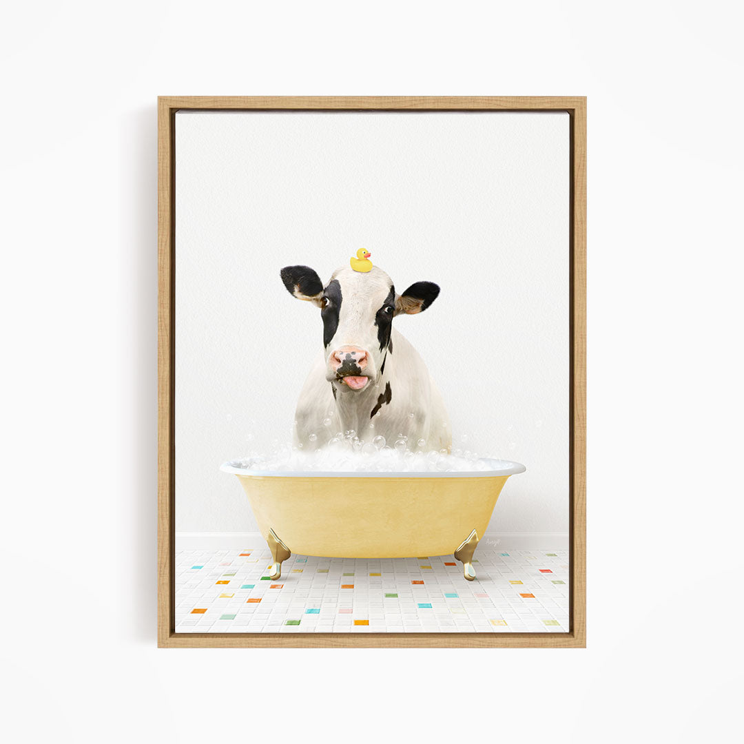 A black and white cow is sitting in a yellow bathtub filled with bubbles, with a rubber duck perched on its head.