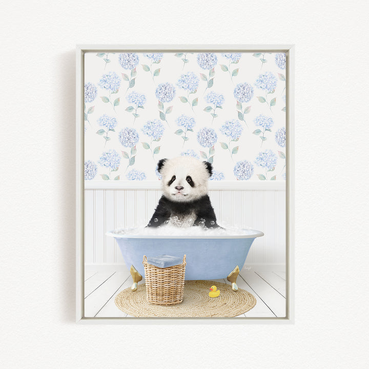 A cute panda bear sitting in a blue bathtub, surrounded by a wicker basket, rubber duckies, and a floral patterned wall behind it.