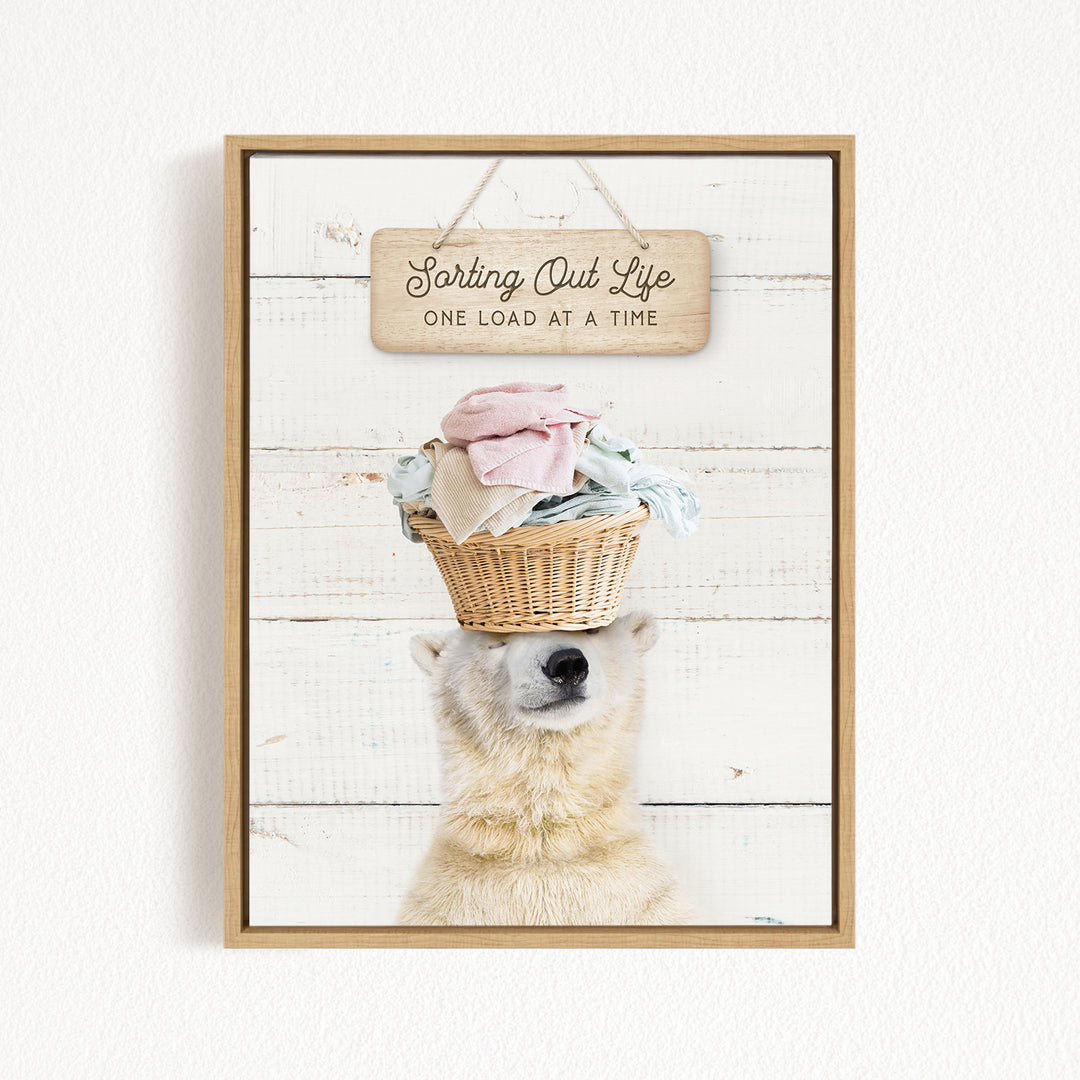 A polar bear balancing a basket of laundry on its head, with a wooden sign above that reads "Sorting Out Life One Load at a Time".