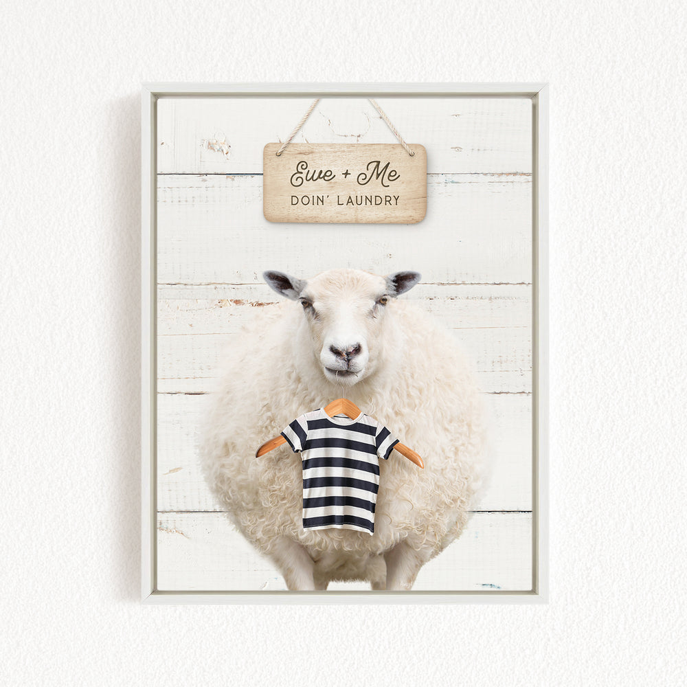 A white sheep wearing a striped shirt stands in front of a wooden sign that says "Eve + Me DO'N Laundry".
