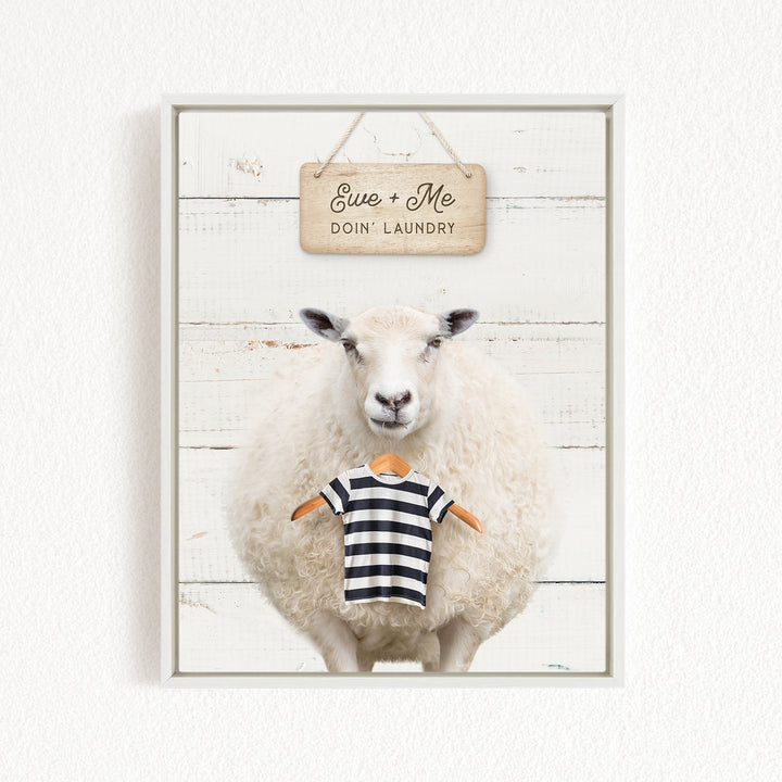 A white sheep wearing a striped shirt stands in front of a wooden sign that says "Eve + Me DO'N Laundry".