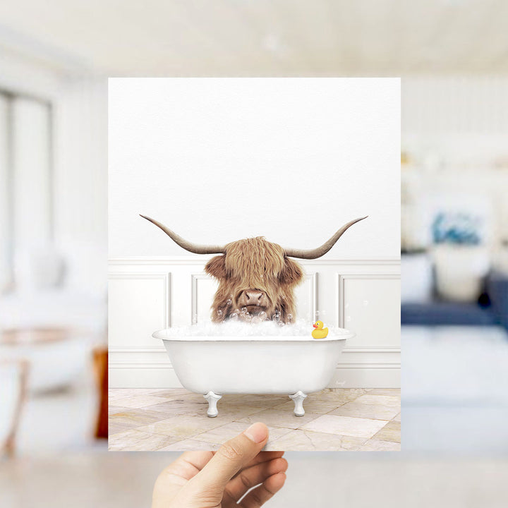 A Highland cow with large horns is sitting in a white bathtub filled with bubbles, with a rubber duck floating in the water.