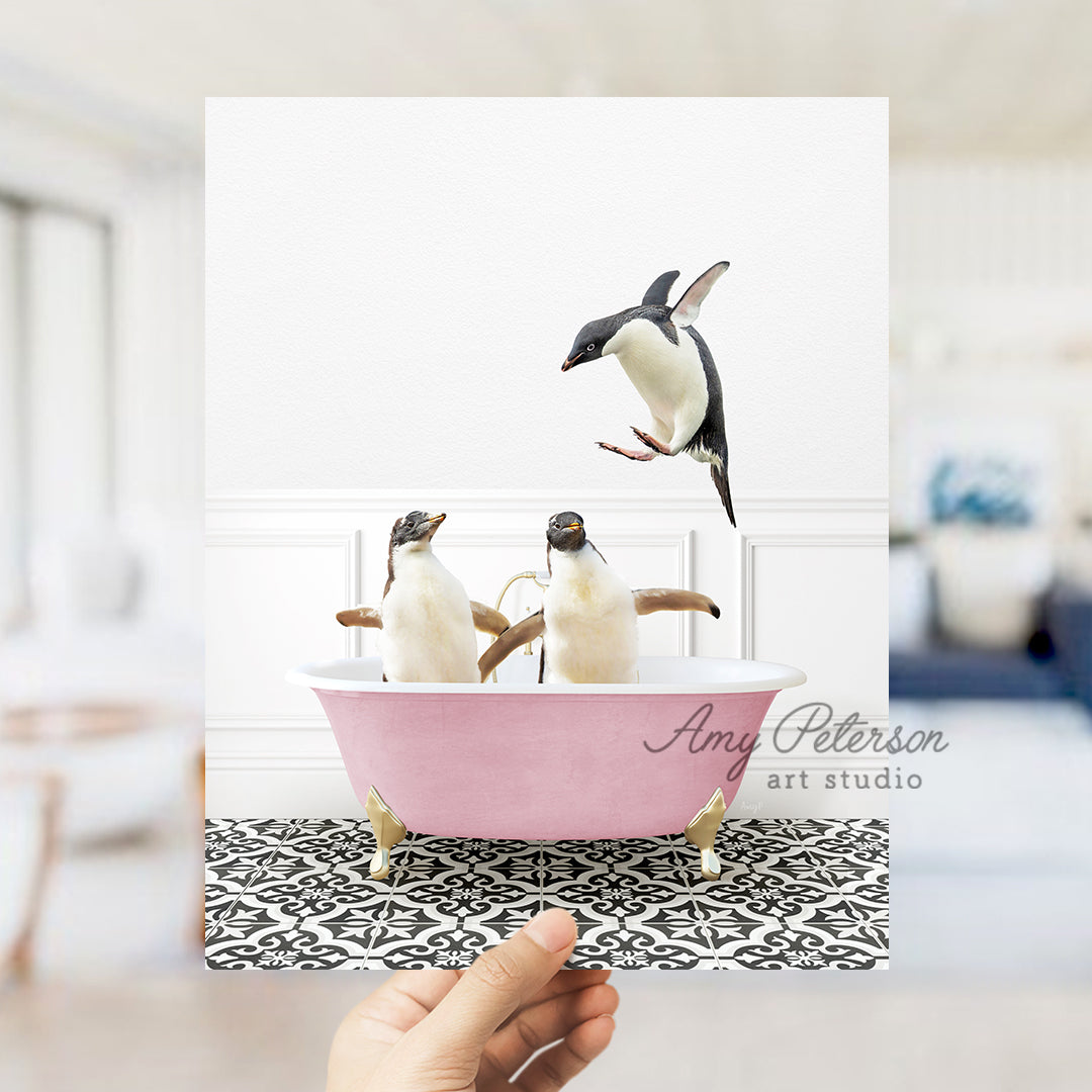 a hand holding a card with three penguins in a bathtub