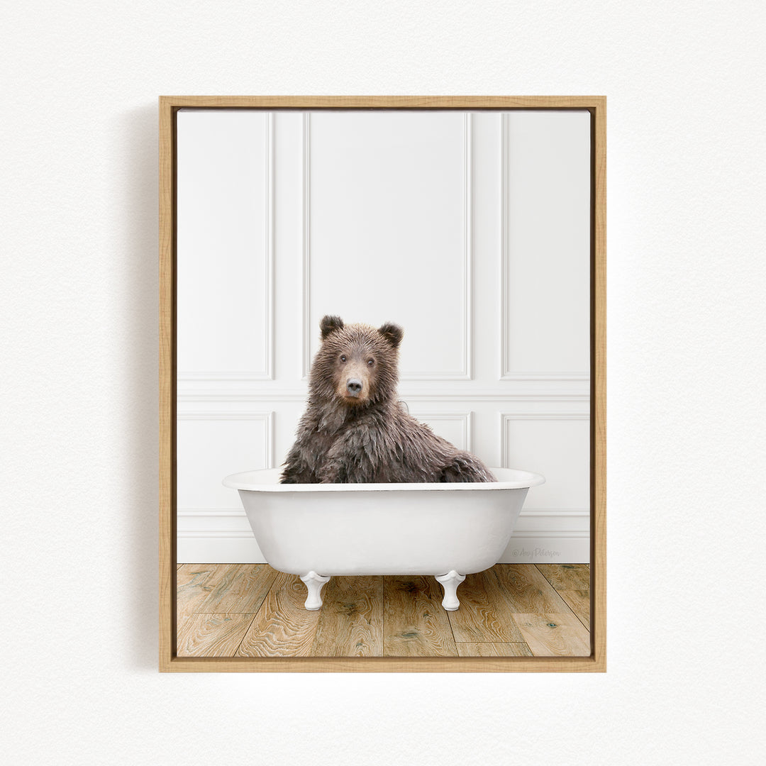A brown bear sitting in a white bathtub against a white wall.