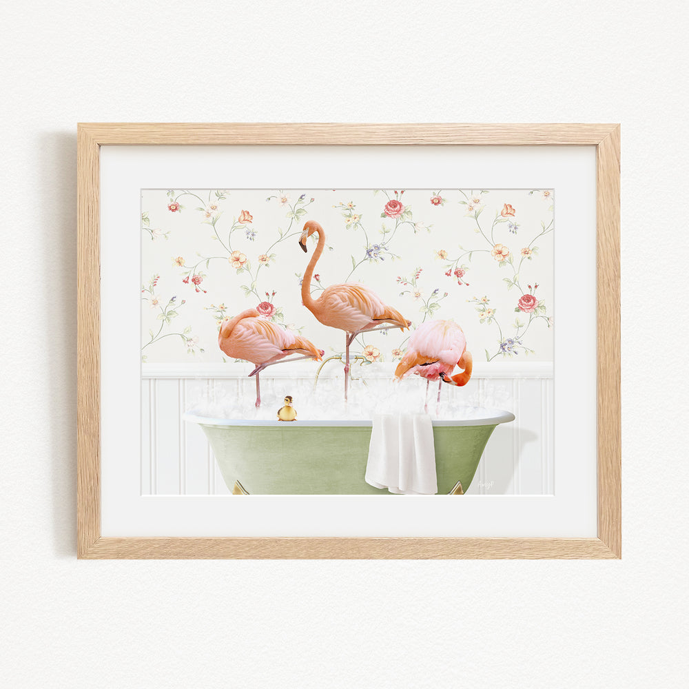 A framed image depicting three flamingos standing in a green bathtub filled with water, surrounded by a floral pattern.