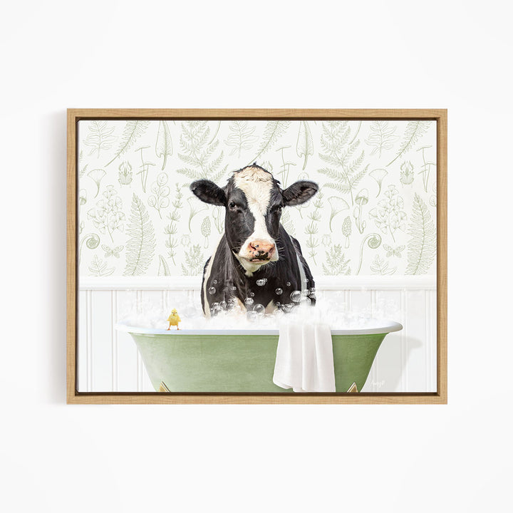 A black and white cow is sitting in a green bathtub filled with bubbles, with a small yellow bird perched on the edge of the tub.