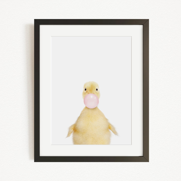 A cute yellow duck blowing a bubble with a pink bubble gum bubble.