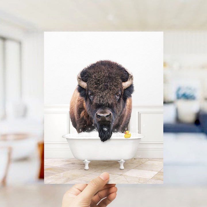 A buffalo with large horns is sitting in a bathtub filled with water, surrounded by a yellow rubber duck.