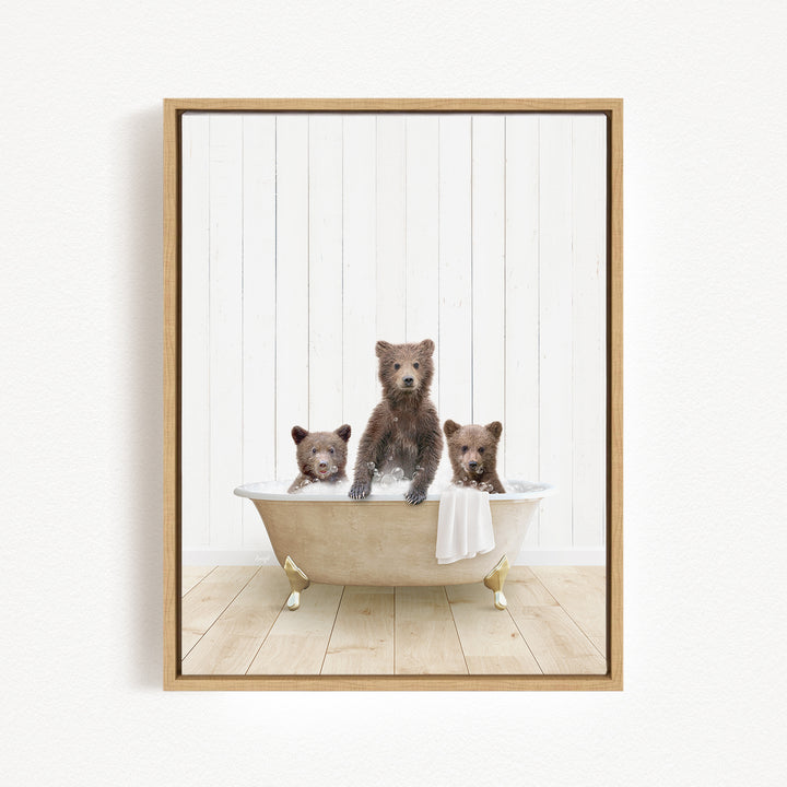 A framed image depicting three adorable brown bears sitting in a bathtub, with one bear standing and the other two sitting.