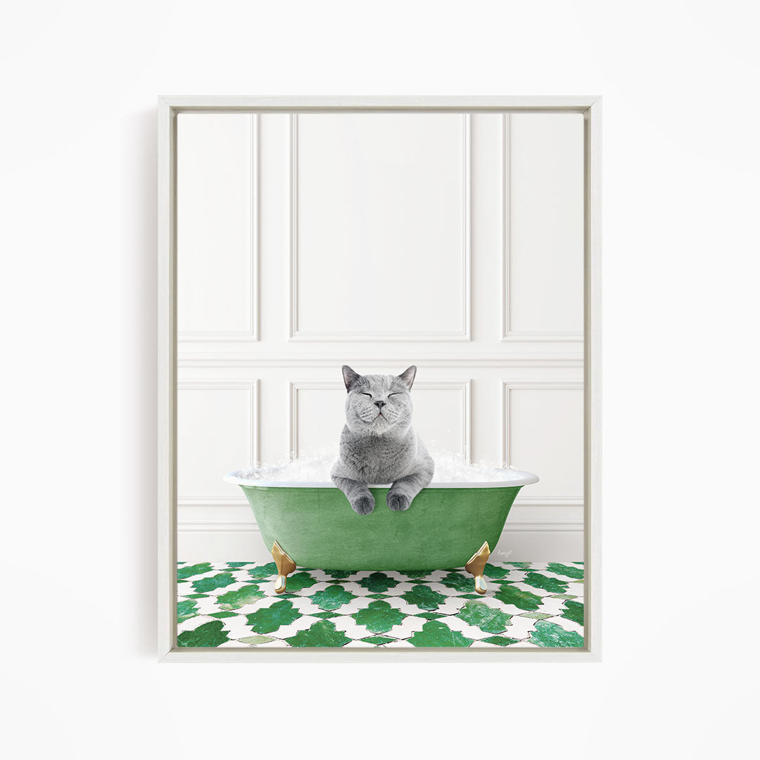 A gray cat sitting in a green bathtub filled with bubbles, with a patterned green and white floor in the background.
