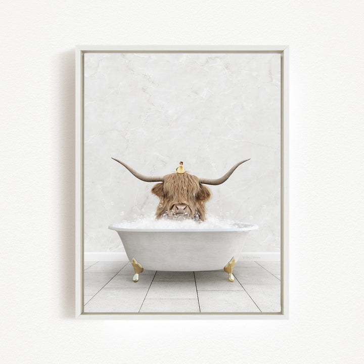 A Highland cow with large curved horns is sitting in a white bathtub filled with bubbles, with a yellow duck perched on its head.