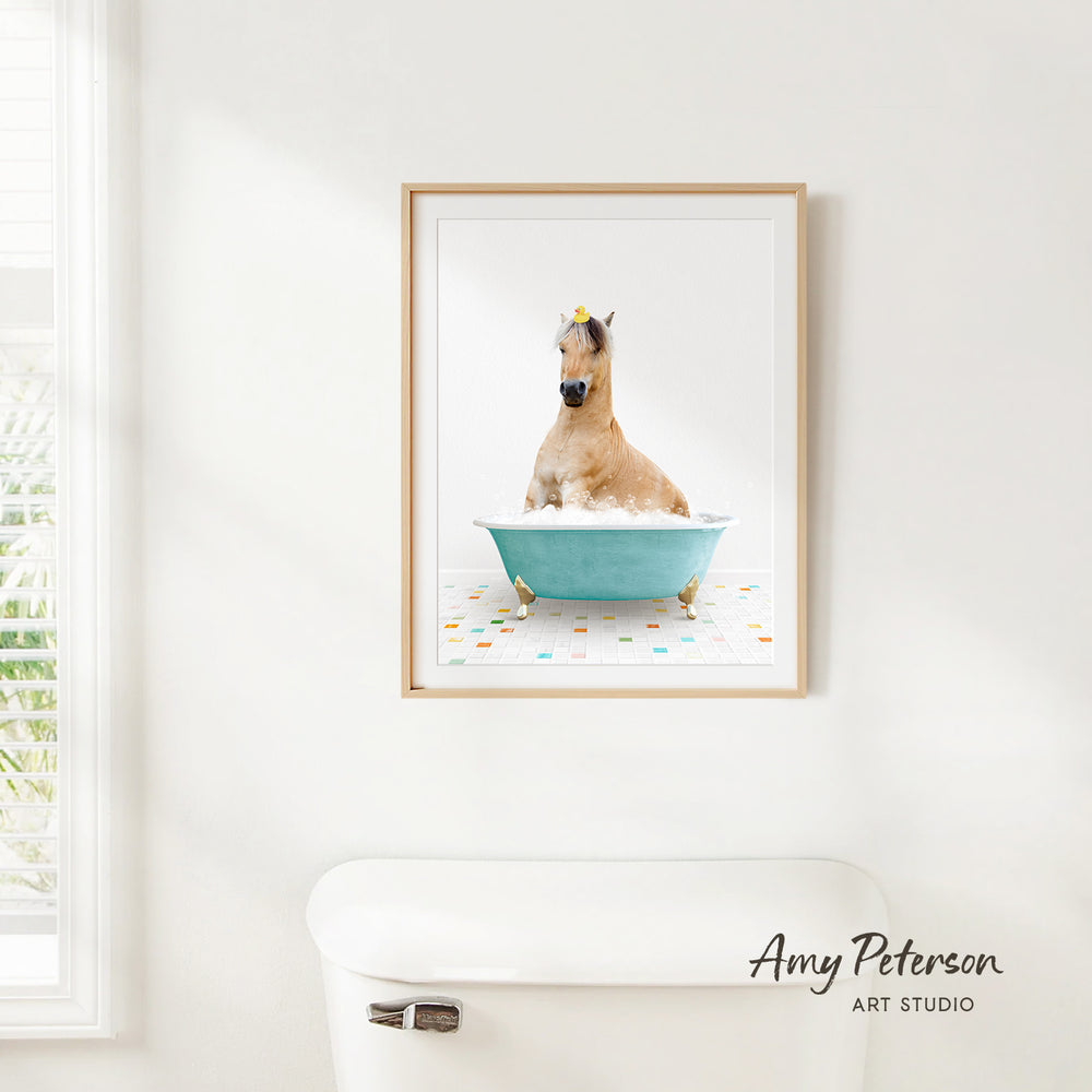 A framed image of a horse sitting in a blue bathtub, surrounded by colorful tiles, is displayed on a white wall.