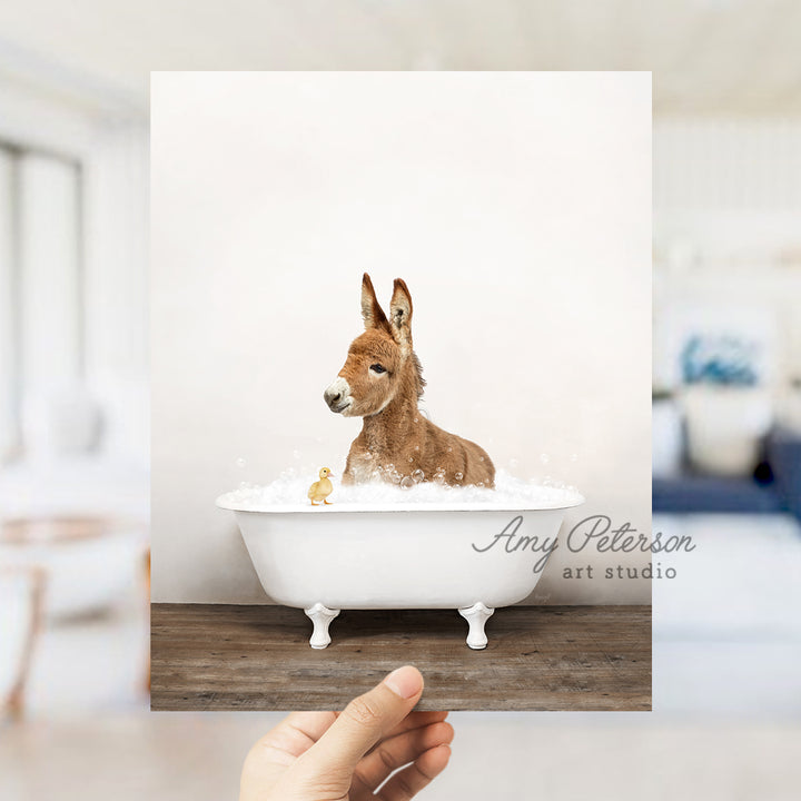 a hand holding up a photo of a dog in a bathtub